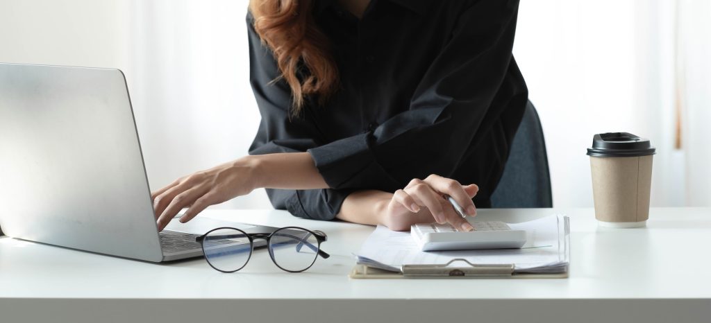 Close up Businessman using calculator and laptop for calaulating finance, tax, accounting