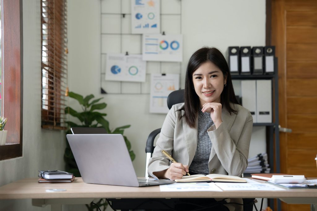 Asian Business woman using calculator and laptop for doing math finance on an office desk, tax